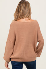 woman wearing a cozy beige maternity sweater with a relaxed fit and loose sleeves, viewed from the back