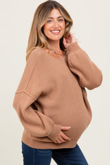 woman wearing a cozy brown ribbed maternity sweater and holding her baby bump