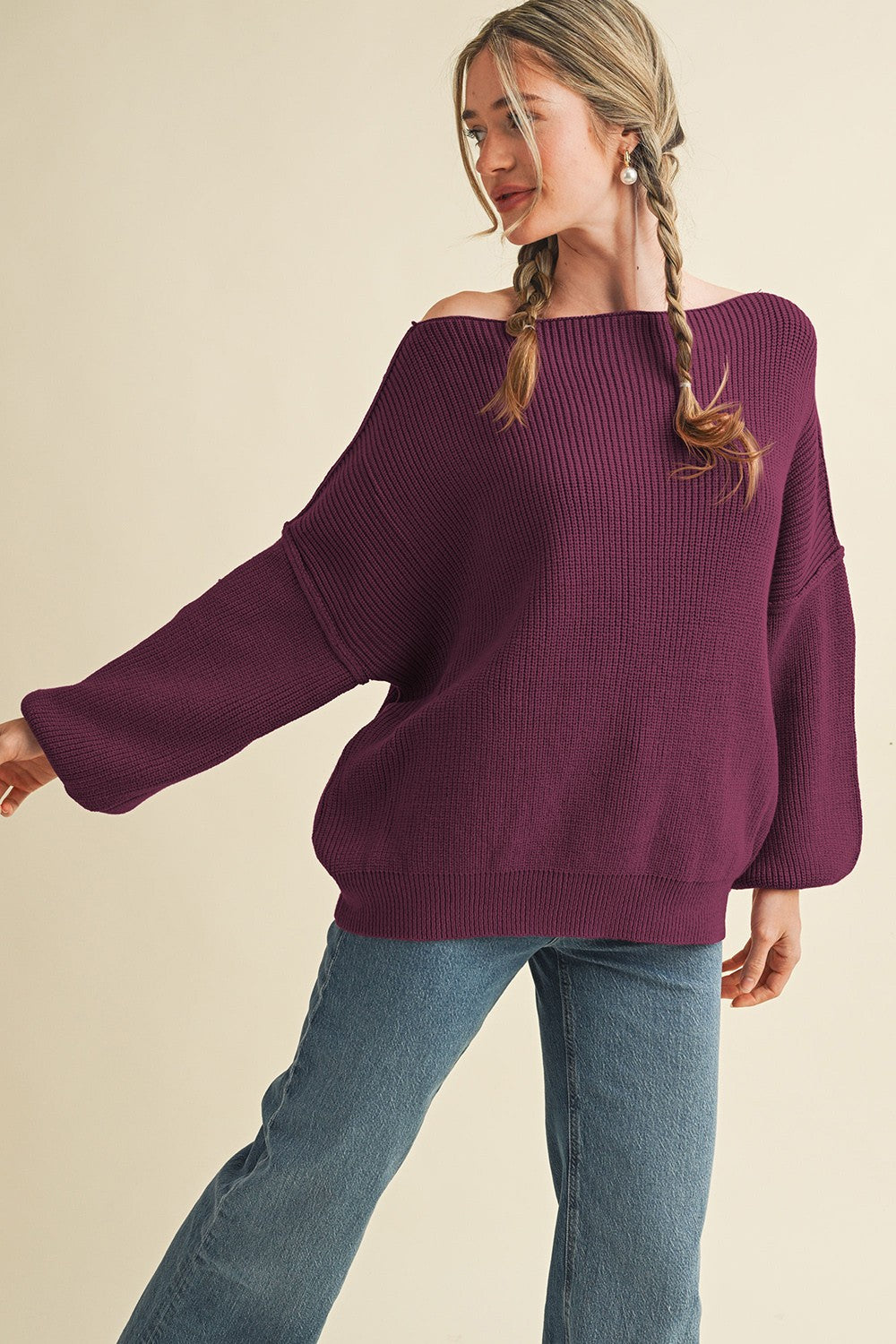 woman wearing a purple off-the-shoulder oversized sweater with ribbed texture and wide sleeves, paired with jeans