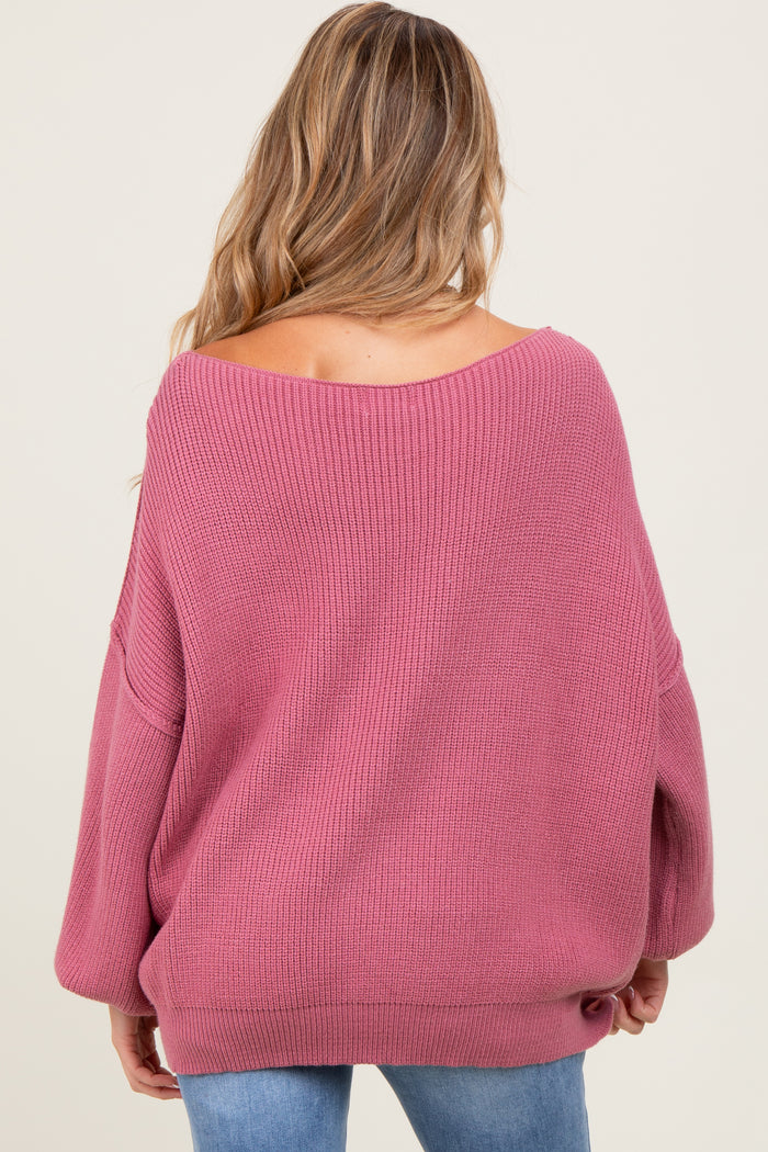 woman wearing a soft pink oversized maternity sweater with a wide neckline and long sleeves