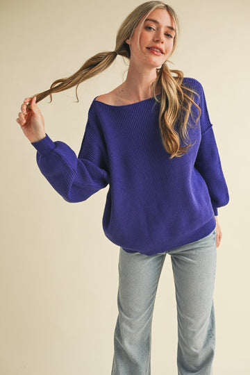 woman wearing a purple off-the-shoulder sweater and light blue wide-leg jeans