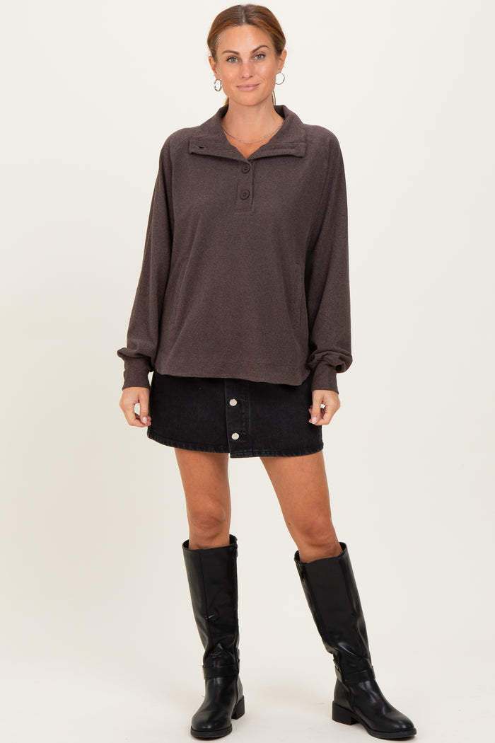 woman wearing a brown pullover sweatshirt with a collar and buttons, paired with a black denim skirt and black knee-high boots
