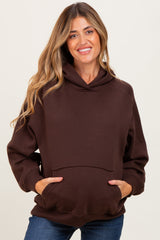 woman wearing a brown oversized maternity hoodie with a pouch pocket and relaxed fit, showing her baby bump