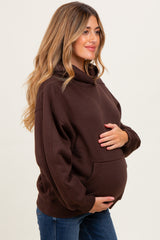 woman wearing a brown maternity hoodie and holding her baby bump
