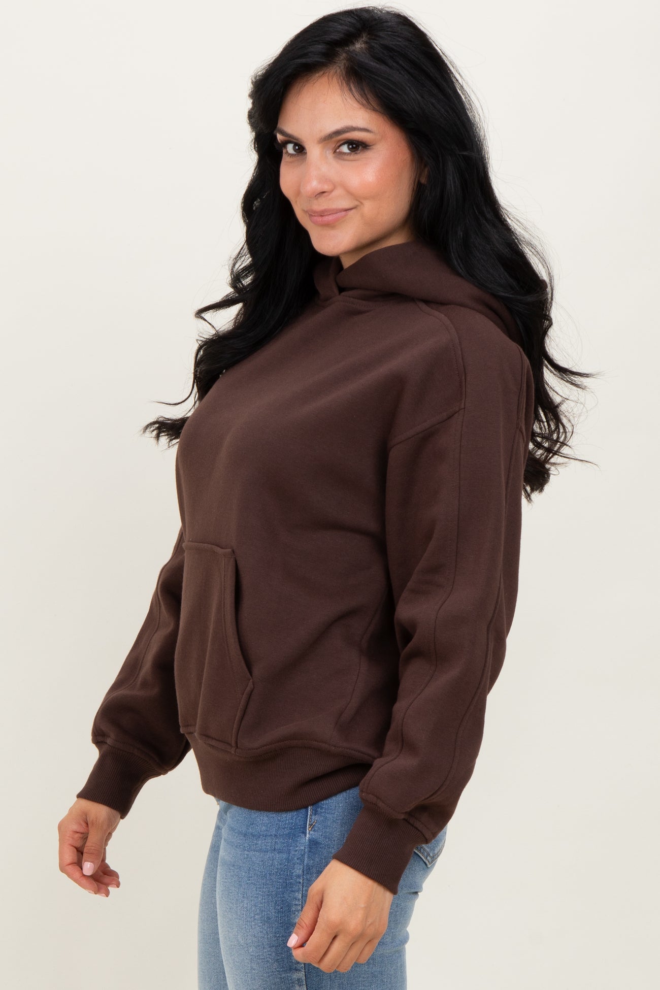 woman wearing a brown oversized hoodie with a front pocket and blue jeans