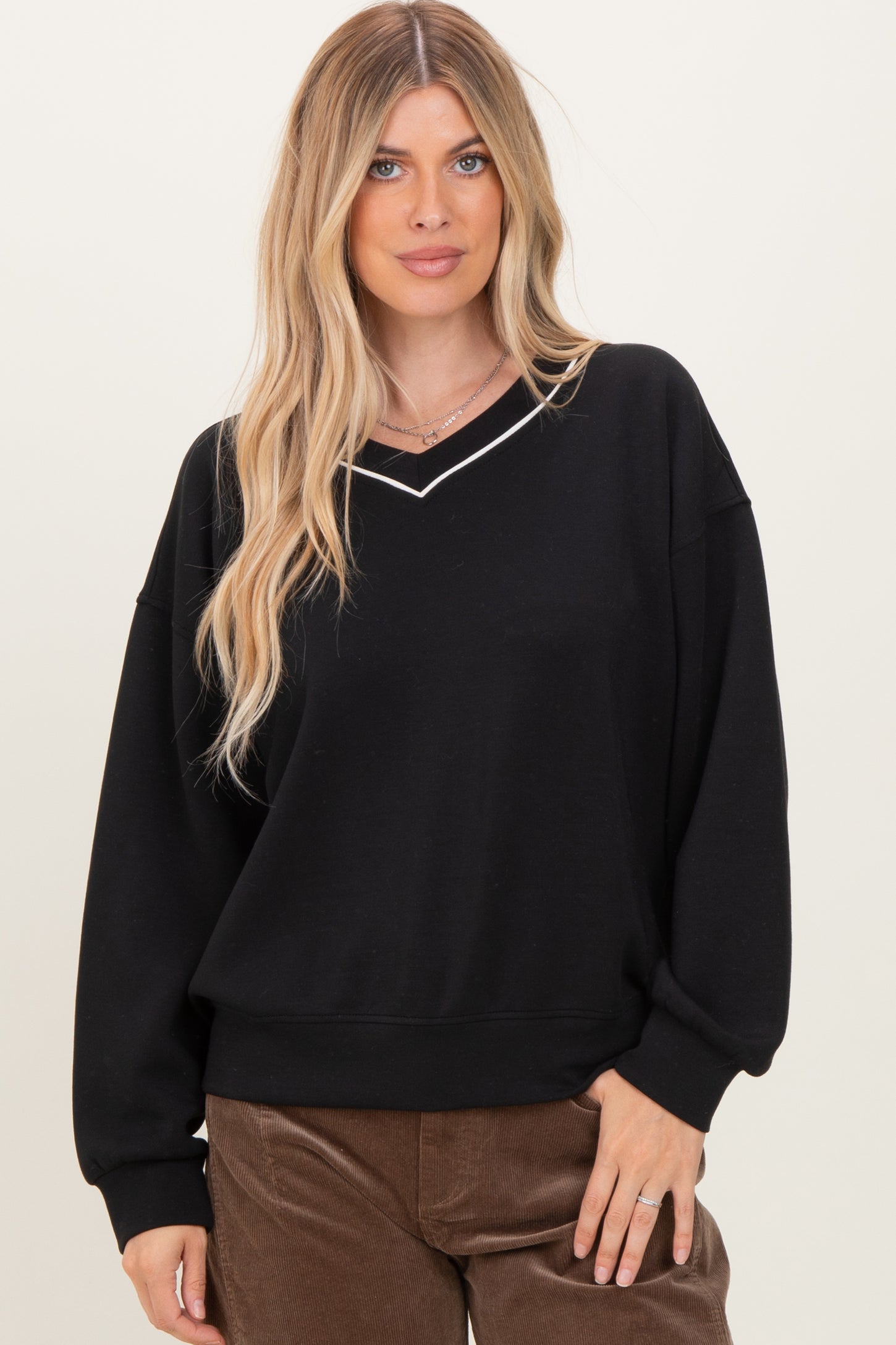 woman wearing a black oversized sweatshirt with a v-neck and contrasting white trim