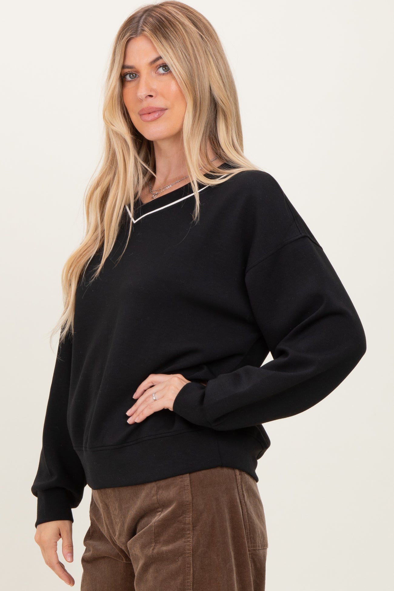 woman wearing a black oversized sweatshirt with a v-neck and long sleeves