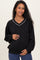 woman wearing a black maternity sweatshirt with a v-neck and white piping, holding her baby bump