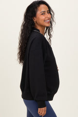 woman wearing a black oversized maternity sweatshirt and showcasing her baby bump