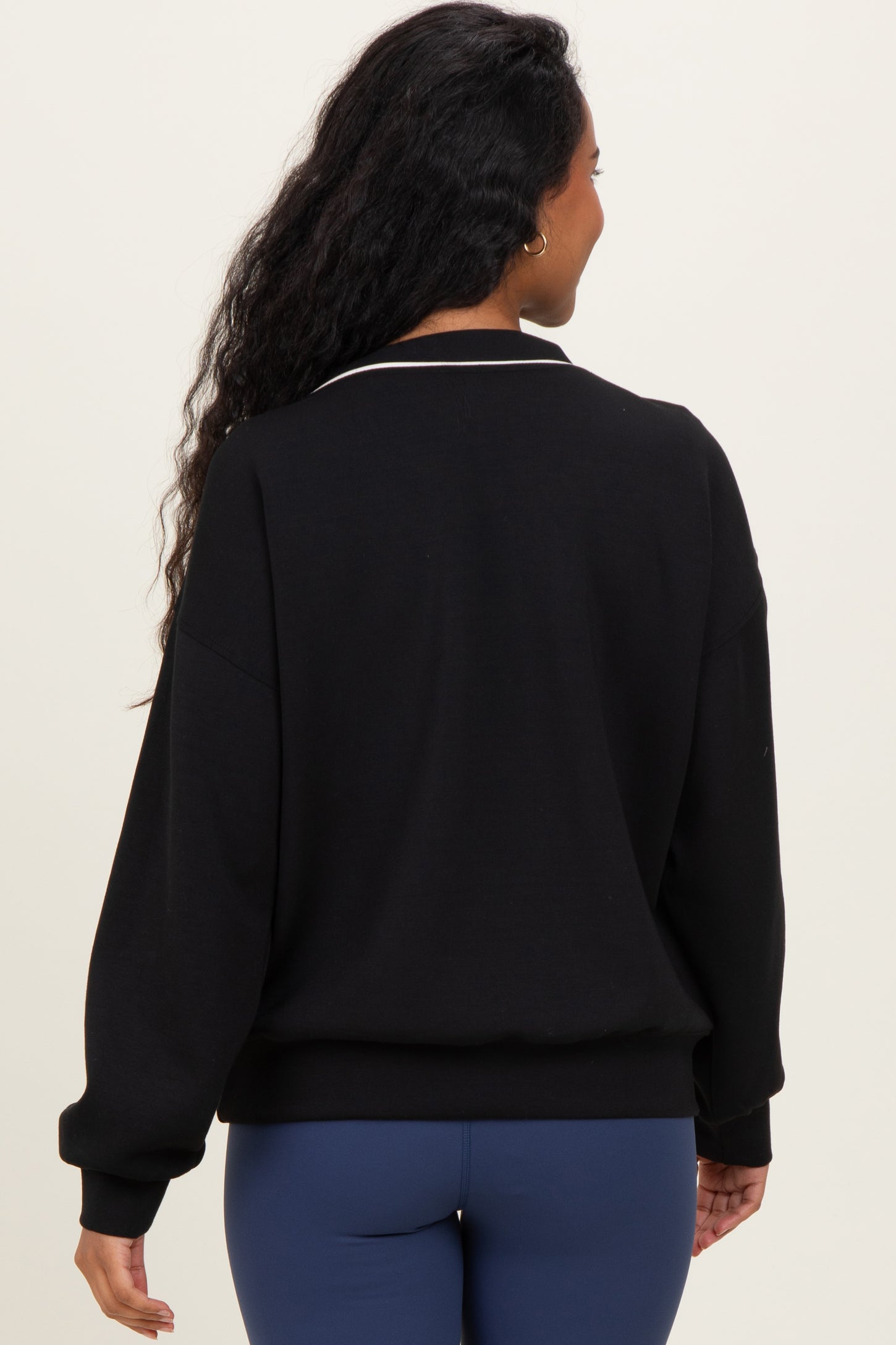 woman wearing a black maternity sweatshirt with a white collar and long sleeves, showing the back view