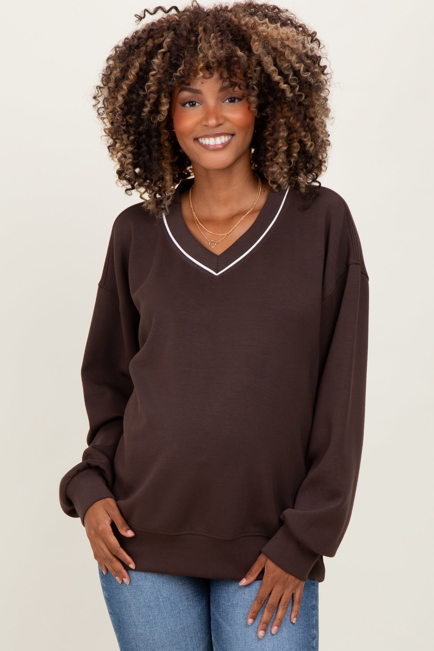 woman wearing a dark brown maternity sweatshirt with a v-neckline and long sleeves, showing her baby bump