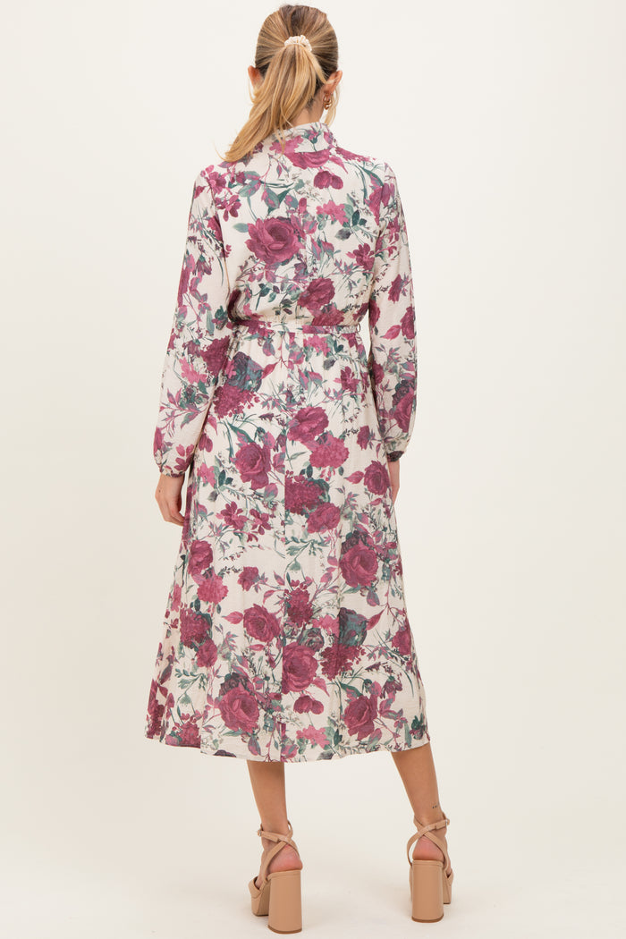 woman wearing a floral long sleeve maternity dress with a cinched waist and ankle-length skirt, showing a baby bump