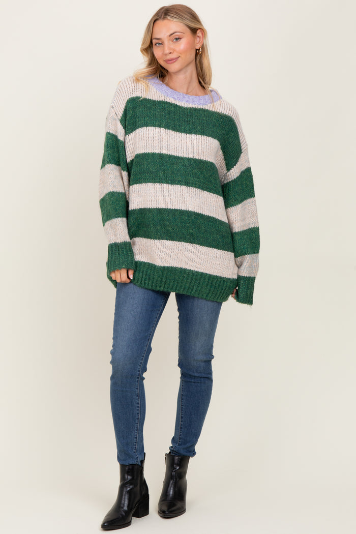 woman wearing a green and cream striped oversized knit sweater with a relaxed fit and blue skinny jeans