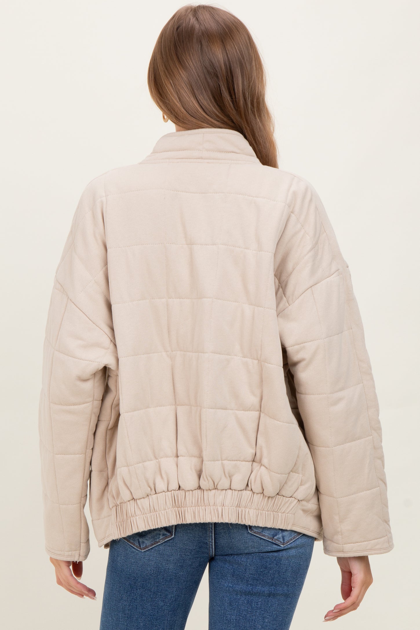 woman wearing a beige quilted maternity jacket with a cinched hem, viewed from the back