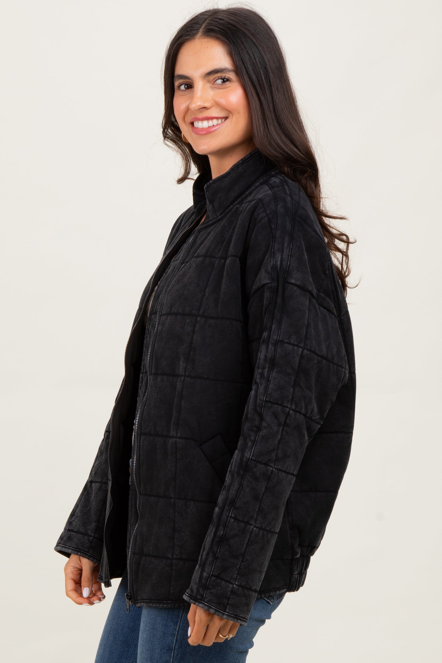 woman wearing a black quilted jacket, smiling with long hair, side view
