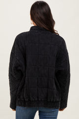 woman wearing a black quilted oversized jacket with a high collar and elastic waistband, viewed from the back