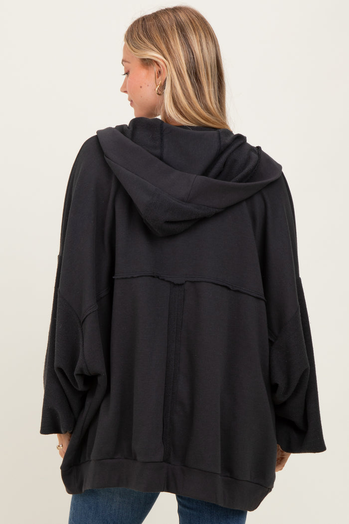 woman wearing a black oversized hoodie with a hood and batwing sleeves, viewed from the back