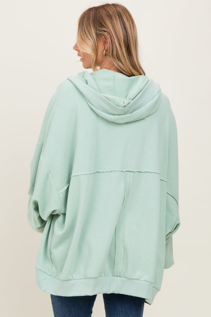 woman wearing a mint green oversized hoodie with a hood and relaxed fit, seen from the back