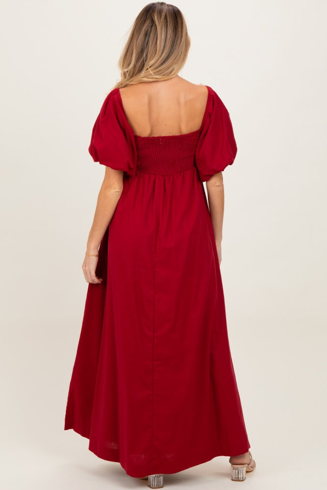 woman wearing a red off-the-shoulder maternity maxi dress with puff sleeves and a shirred bodice, showing a baby bump