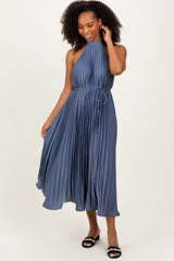 woman wearing a pleated slate blue midi dress with a halter neck and a tie waist detailing