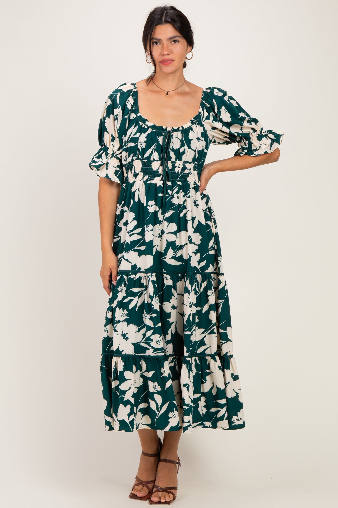 woman wearing a dark green floral print maxi dress with puff sleeves and tiered ruffles