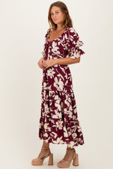 woman wearing a burgundy floral maxi dress with ruffle sleeves and tiered hem, paired with beige platform heels