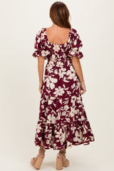 woman wearing a maroon floral maxi dress with puff sleeves and a tiered skirt, viewed from the back