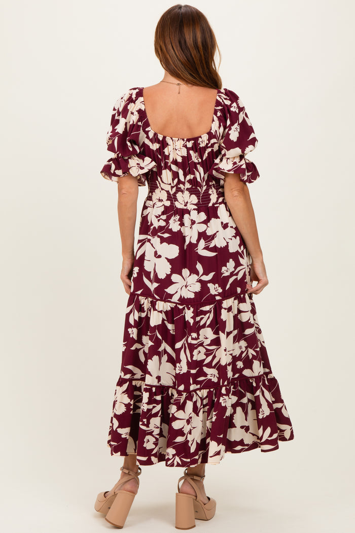 woman wearing a maroon floral maxi dress with puff sleeves and a tiered skirt, viewed from the back