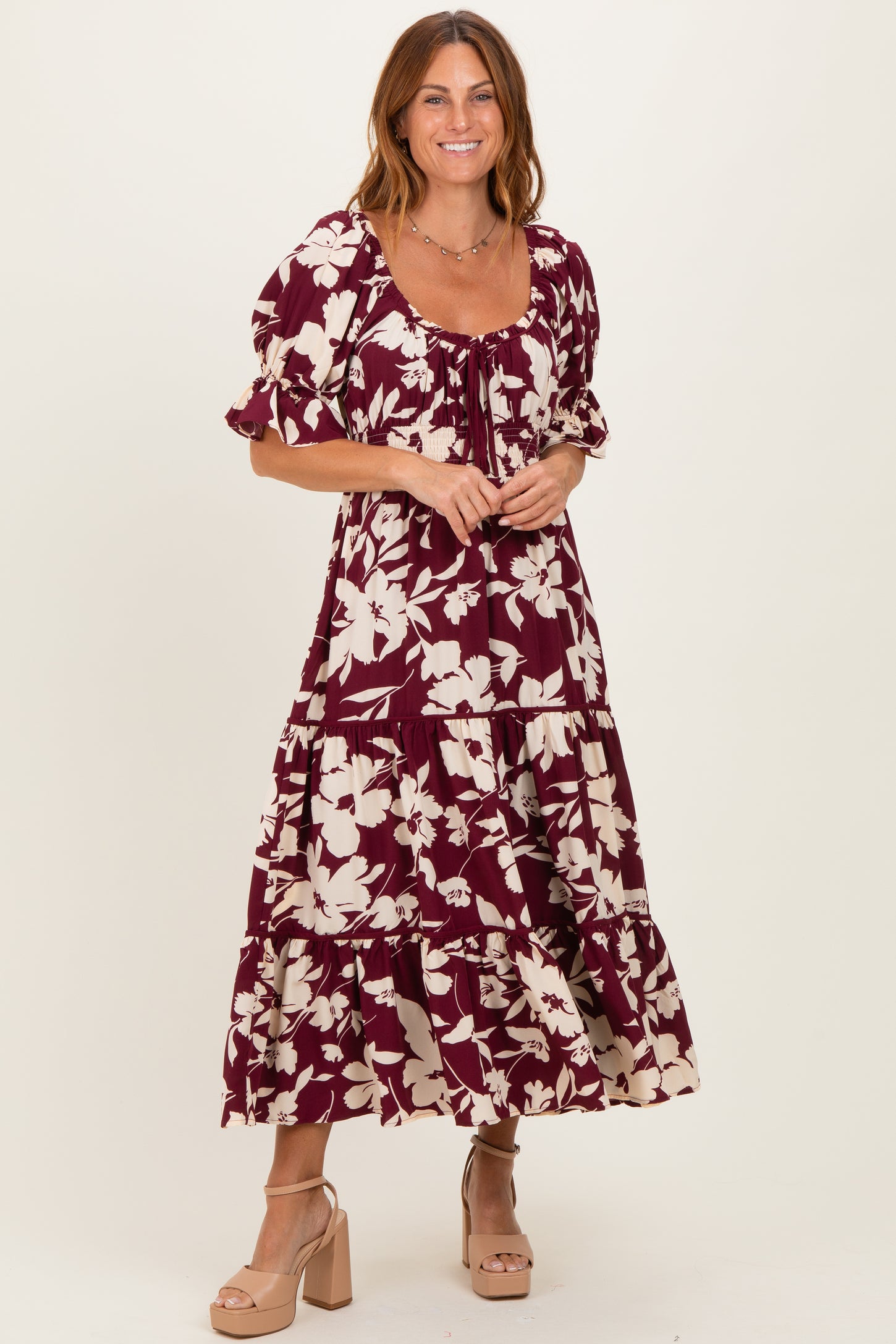 woman wearing a burgundy floral tiered maxi dress with puff sleeves and a square neckline