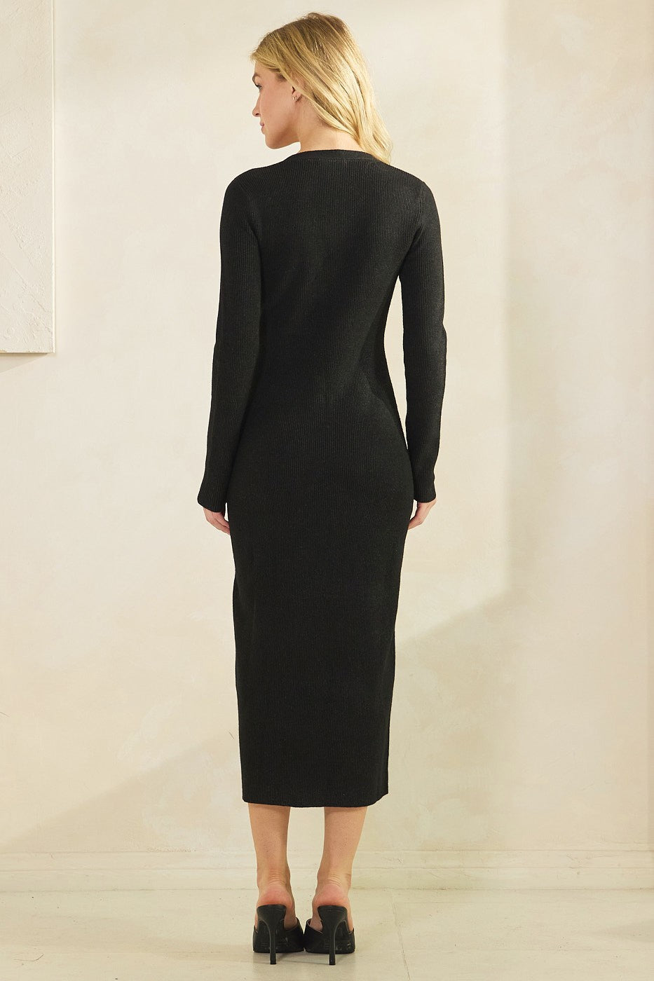 woman wearing a form-fitting black ribbed knit maxi dress with long sleeves and back detail