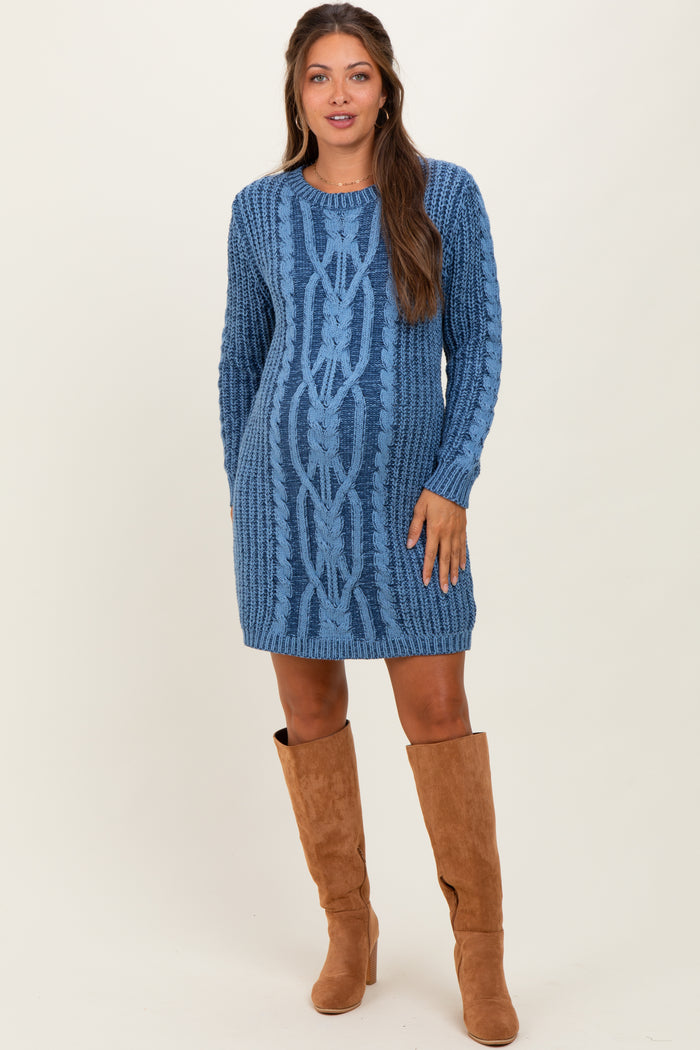 woman wearing a blue cable knit maternity sweater dress with long sleeves and knee-high brown boots, showing her baby bump
