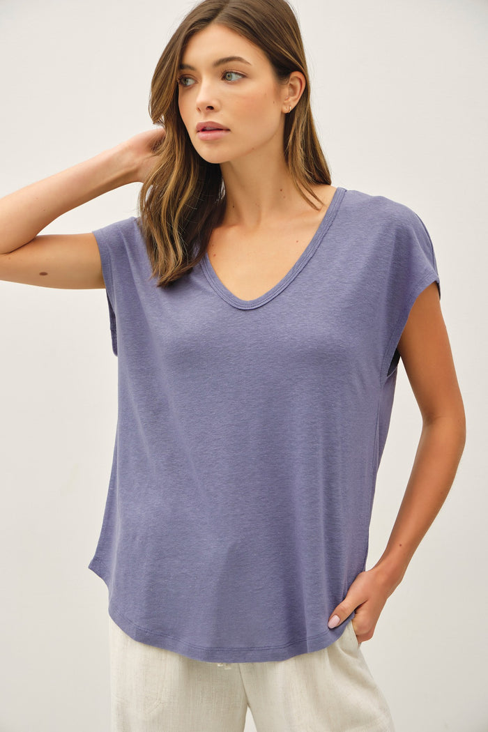 woman wearing a purple short sleeve v-neck top with a relaxed fit and side pockets