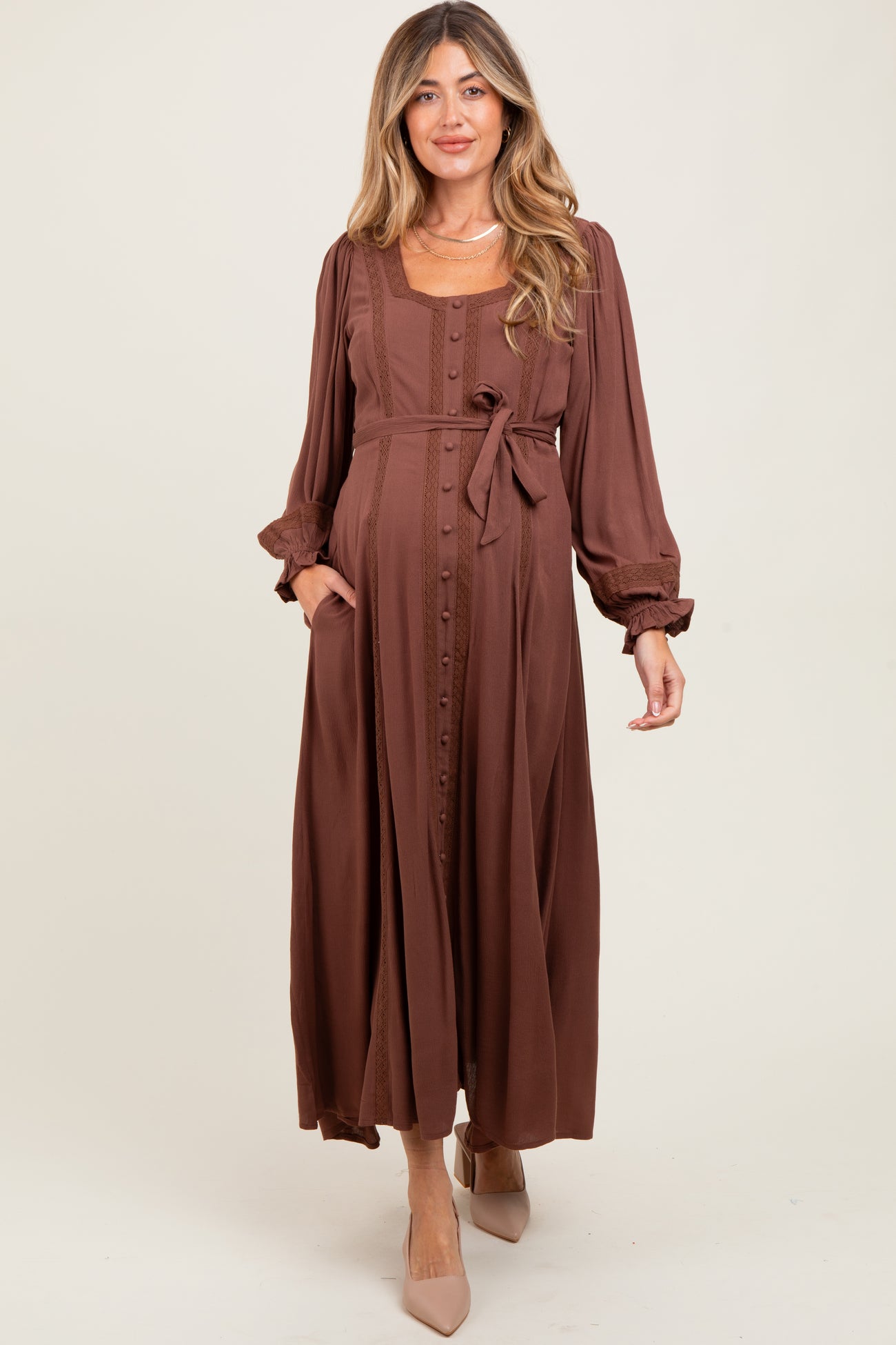 woman wearing a brown long sleeve maternity dress with buttons and a tie waist, featuring a relaxed fit and pockets