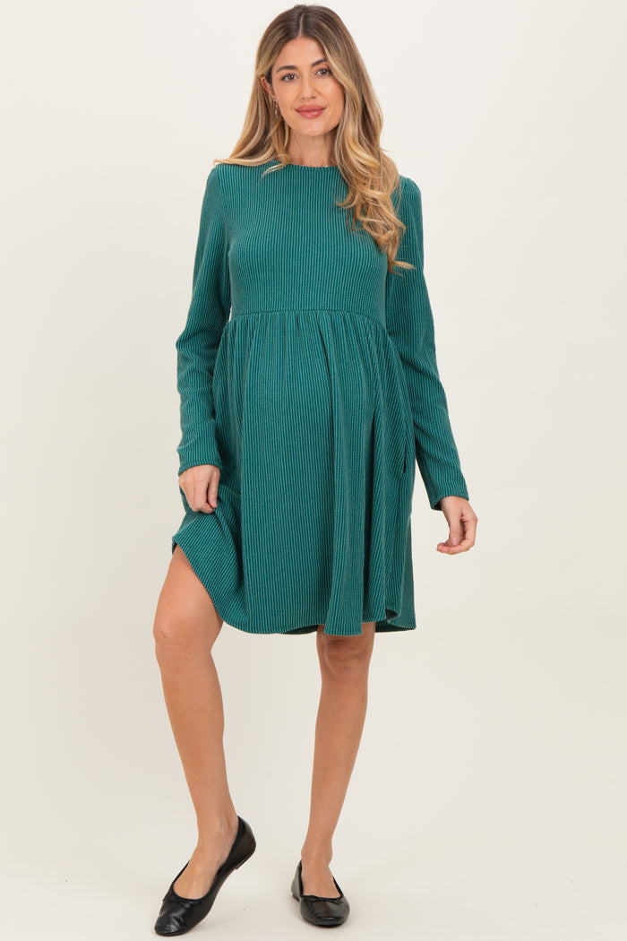 woman wearing a green striped long sleeve maternity dress with a fitted bodice and flowing skirt, showing her baby bump
