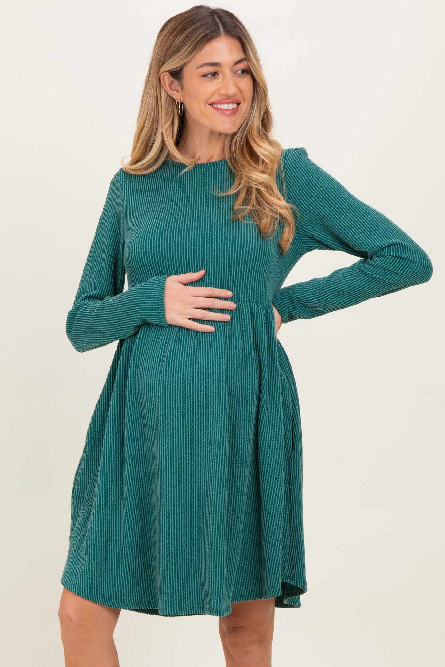 woman wearing a green ribbed long sleeve maternity dress with a loose fit and a visible baby bump