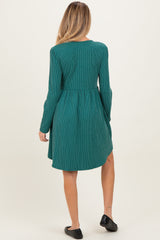 woman wearing a green striped maternity dress with long sleeves and a flared skirt
