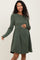 woman wearing a dark green ribbed long sleeve maternity dress with a baby bump visible
