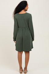 woman wearing a green striped maternity dress with long sleeves and a relaxed fit, showing the back view