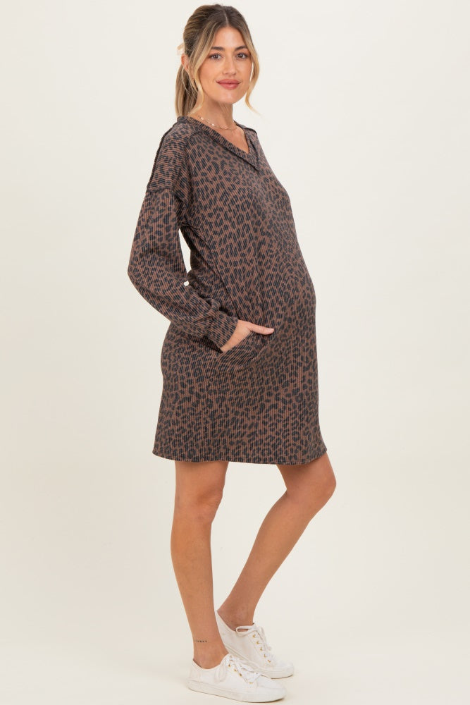 woman wearing a brown printed maternity dress with long sleeves and pockets, showcasing her baby bump