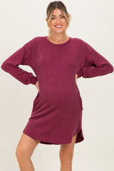 woman wearing a burgundy ribbed maternity dress with long sleeves and side slits, showcasing her baby bump
