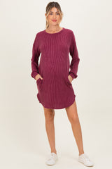 woman wearing a berry striped maternity sweater dress with pockets and long sleeves, standing against a neutral background
