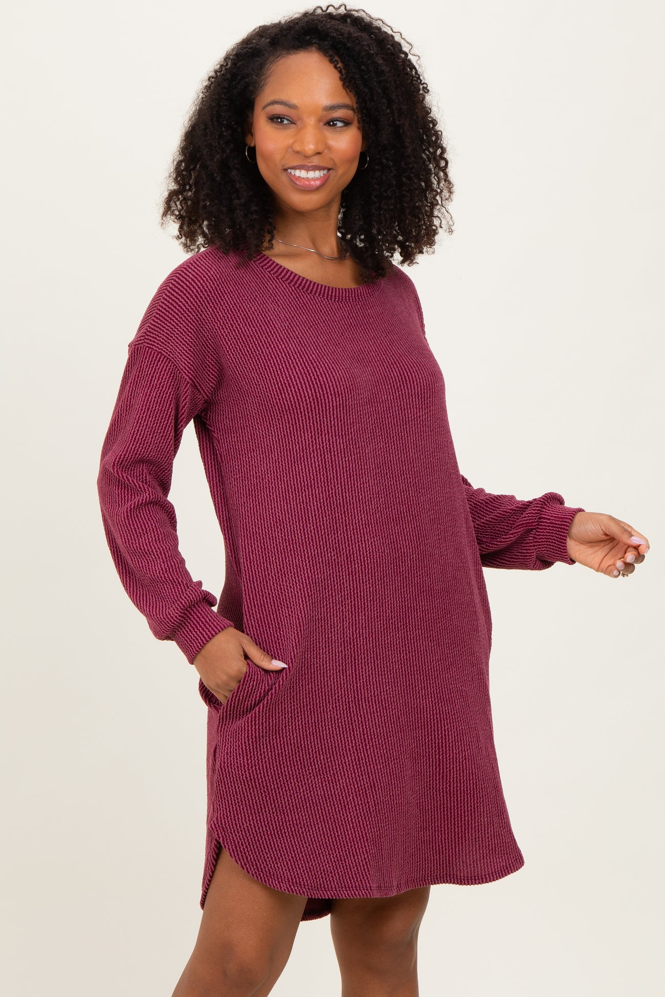woman wearing a burgundy long sleeve ribbed dress with side pockets and a relaxed fit