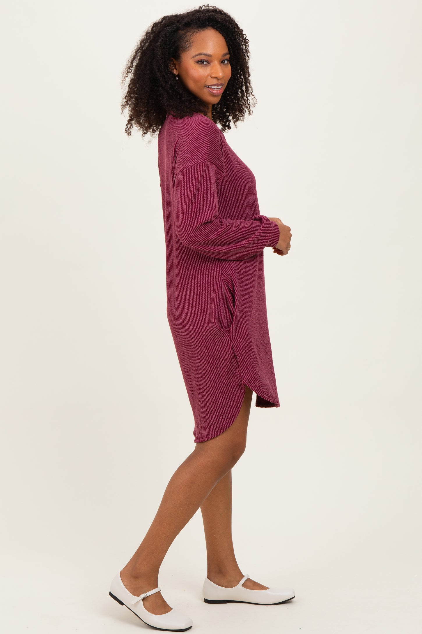 woman wearing a burgundy ribbed long sleeve dress with side pockets and a relaxed fit