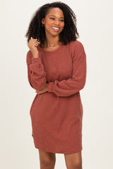 woman wearing a rust-colored ribbed long sleeve dress with a relaxed fit and subtle side slits