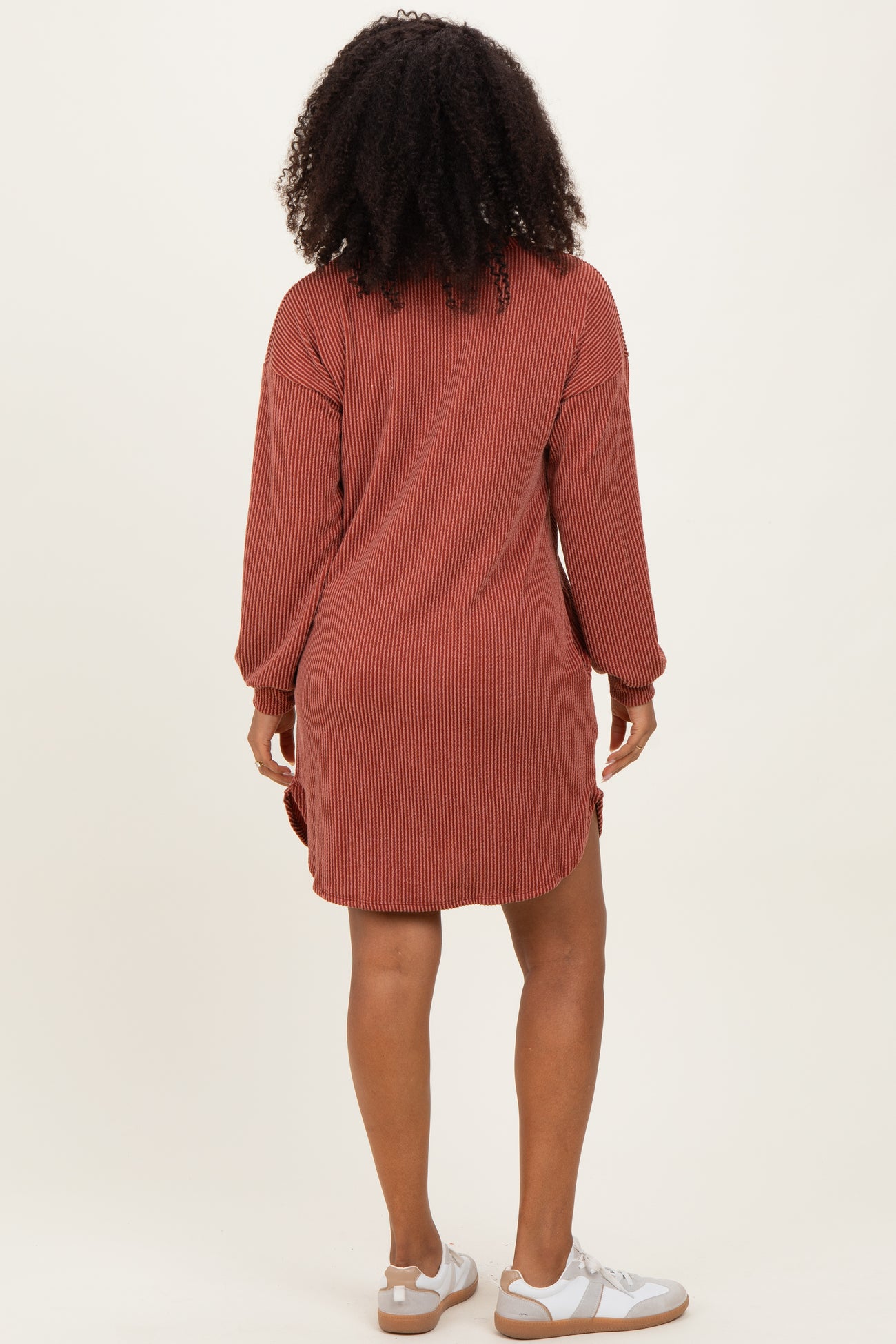 woman wearing a rust striped long sleeve shirt dress with side slits and white sneakers