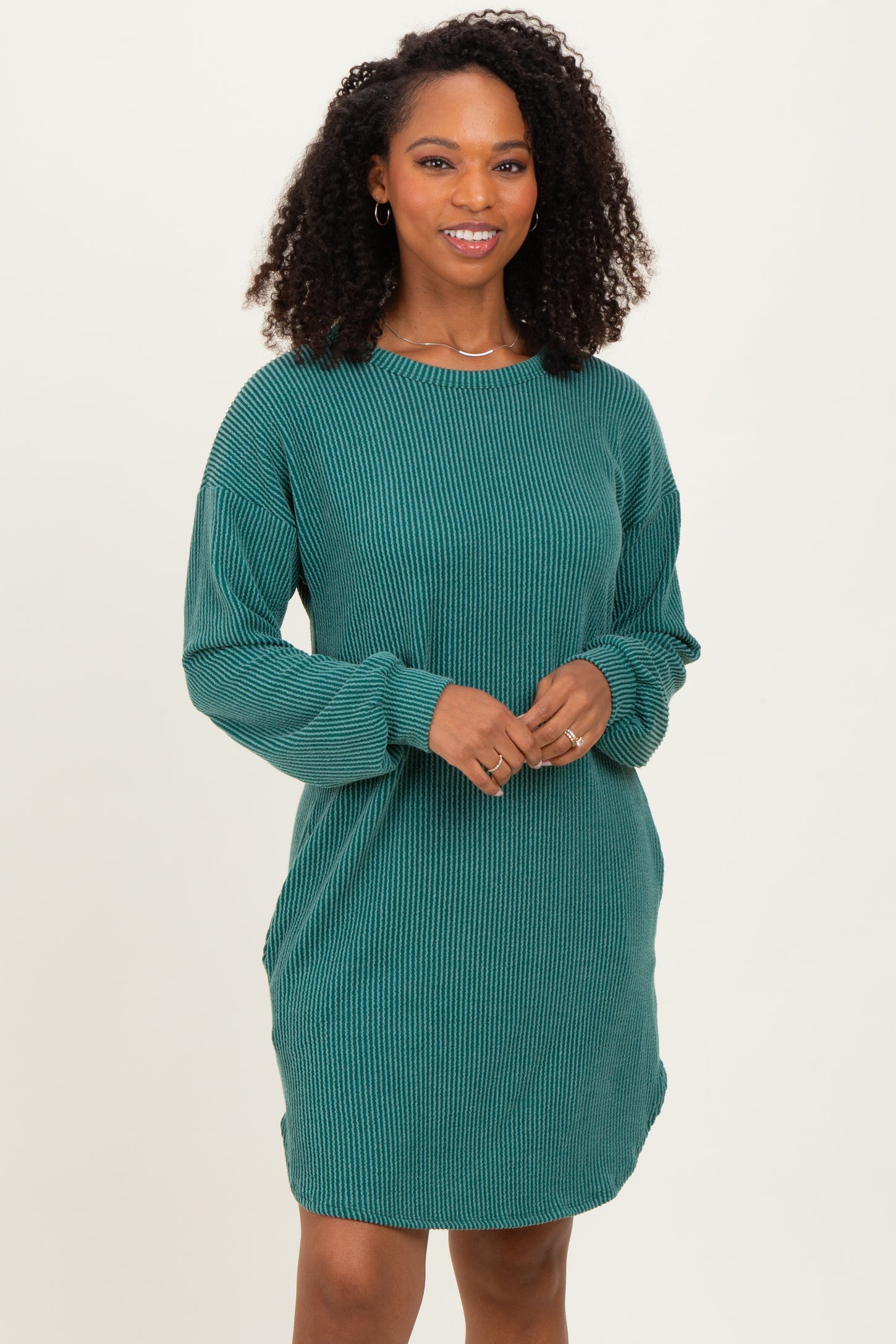 woman wearing a teal ribbed long sleeve dress with side pockets and a relaxed fit