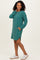 woman wearing a teal striped long sleeve dress with pockets and side slits, paired with white sneakers
