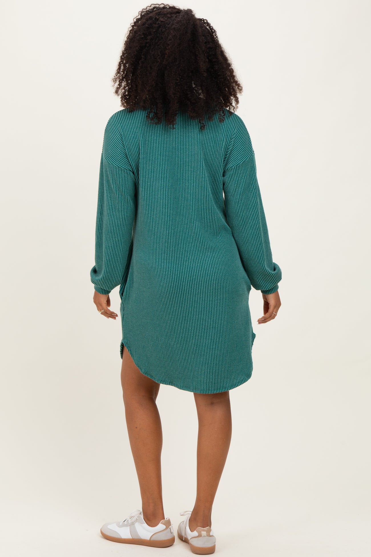 woman wearing a green striped oversized shirt dress with long sleeves and side slits, shown from the back