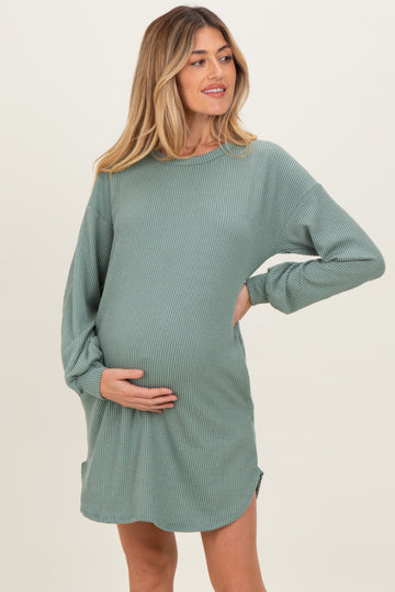 woman wearing a green ribbed long sleeve maternity dress and cradling her baby bump