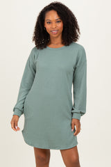 woman wearing a ribbed long sleeve dress in green with a relaxed fit and side slits